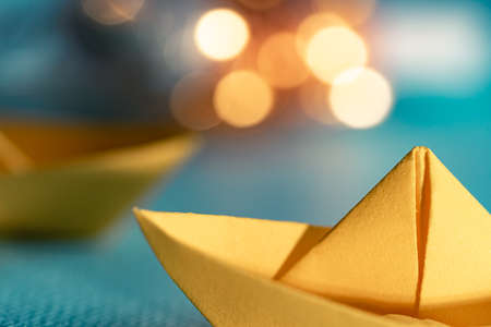 Origami yellow sailing boat on a sea made with blue paper. Paper art style background with ship,...