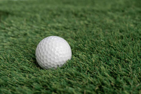 Golf ball on green artificial grass, top view with space for text - macro, selective focus, space...