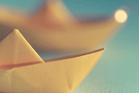 Origami yellow sailing boat on a sea made with blue paper. Paper art style background with ship,...