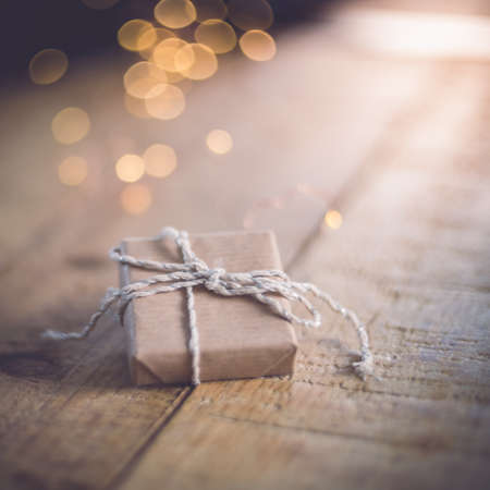 Close-up of a gift wrapped with craft paper on a wooden table. beautiful bokeh light in the background. eco friendly conceptの写真素材