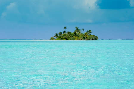 Uninhabited tropical island with palm trees. stormy sky and turquoise lagoon
