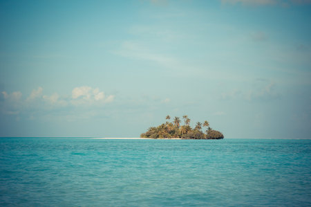Uninhabited tropical island with palm trees. stormy sky and turquoise lagoonの写真素材