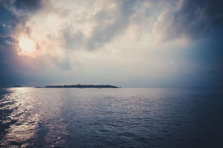 Tropical island with palm trees at sunset on a stormy day.の写真素材