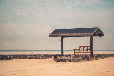 isolated bench on a tropical beach looking at the horizon.