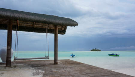 Swing on a tropical beach. isolated idyllic island with boats in the backgroundの写真素材