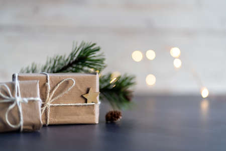 Christmas and zero waste, eco friendly packaging. wrapped gifts in craft paper with wooden snowflakes and star on a wooden background. ecological Christmas holiday concept, eco decor with woodの写真素材