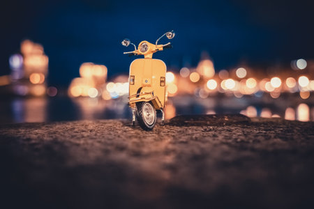 Vintage yellow toy motorcycle in front of the port of La Rochelle at nightの写真素材