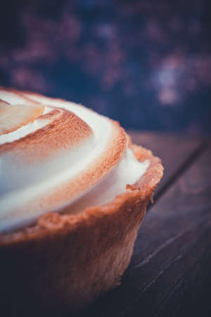 Close-up of a traditional french lemon tart on a dark wooden table. selective focus with shallow...
