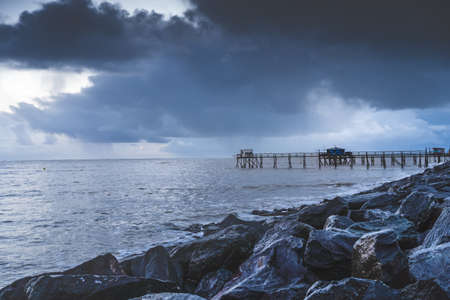 Typical old wooden fishing huts on stilts called âcarreletâ in the atlantic ocean near La Rochelle, France. shot taken at sunset on a stormy day.の写真素材