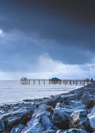 Typical old wooden fishing huts on stilts called âcarreletâ in the atlantic ocean near La Rochelle, France. shot taken at sunset on a stormy day.の写真素材