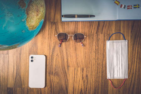 World map and items on wooden background, flat lay. summer travel wanderlust concept, space for text. map camera sunglasses passport phone pen mask book on wooden background top view. vacation planning concept.の写真素材