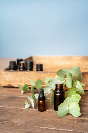 Essential oils in small glass bottles with eucalyptus sprigs on a grey background. Selective focus and copy space for text. Natural cosmetic products.の写真素材