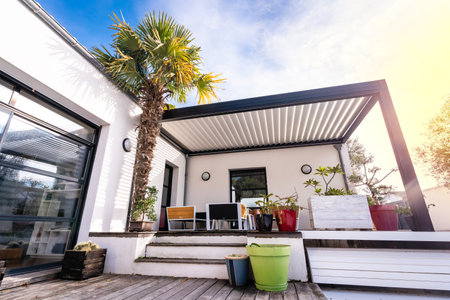 Trendy outdoor patio pergola shade structure, awning and patio roof, garden lounge, chairs, metal grill surrounded by landscapingの写真素材