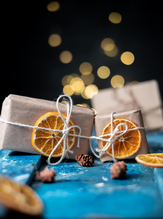 Eco-friendly kraft paper wrapping gifts with dried orange slices on a blue table. DIY gifts, eco-decor. portrait sizeの写真素材