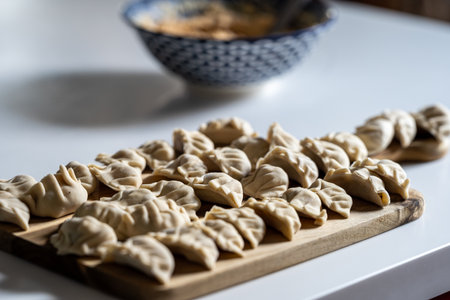 raw gyoza, before cooking, on a wooden board. close-up view in the kitchen