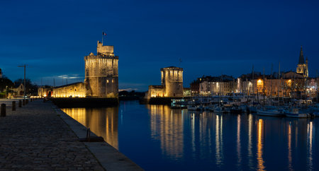 beautiful illuminated cityscape of the old harbor of La Rochelle at night with festive ciyilightsの写真素材