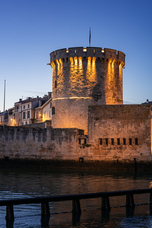 beautiful illuminated cityscape of the old harbor of La Rochelle with its famous tower "la chaine"の写真素材