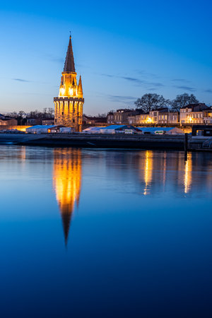 beautiful illuminated cityscape of the old harbor of La Rochelle with its famous tower "la lanterne"の写真素材