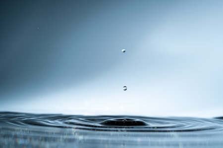 Close-up of a water drop and splash background, small impact causes big changes. Ripple, macro wave on surface of liquidの写真素材