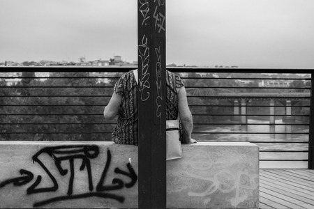 Senior woman sitting on a bench, enjoying the view of the riverのeditorial素材