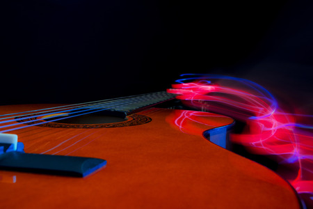 Classic guitar of red wood against black background with light effectsの写真素材