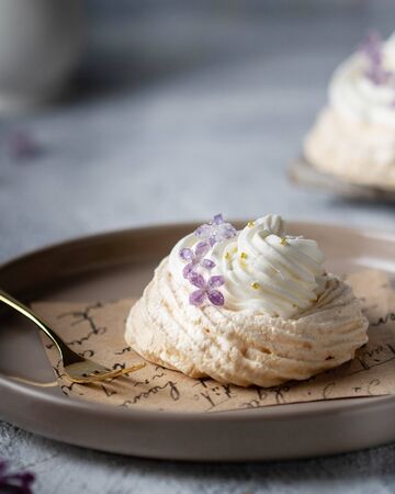 Pavlov's cake with meringue and whipped cream, decorated with candied lilacsの写真素材