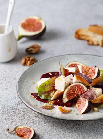Fresh salad of beets, cheese, chicken figs on a gray plateの写真素材