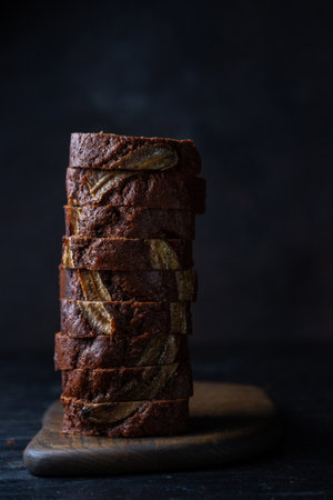 Sliced â€‹â€‹chocolate muffin with banana, banana bread, vertically on a wooden board on...