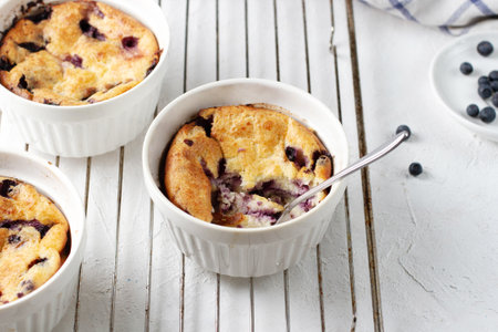 Cottage cheese casserole with blueberries in a portioned cup, broken by a spoon, stands on the wire...