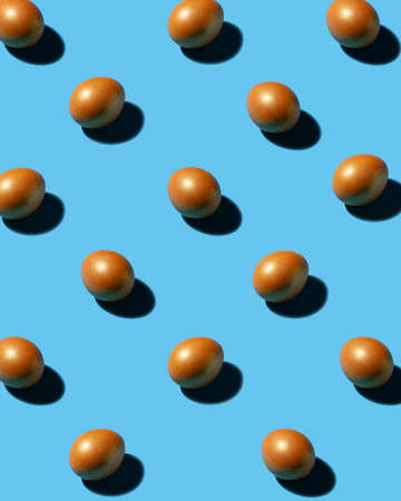 A pattern of golden eggs on a blue background, bright light, clear shadows. Painted eggs for Easter.の写真素材