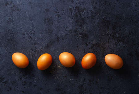 Orange golden glitter eggs on dark blue background with texture, row, free space