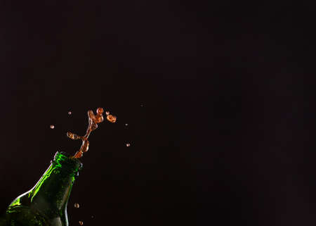 Neck of glass green transparent bottle with splashes of vinous drink, juice or lemonade on black background, free spaceの写真素材
