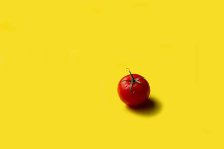 Red tomato with water drops on a yellow background, free space, isolateの写真素材