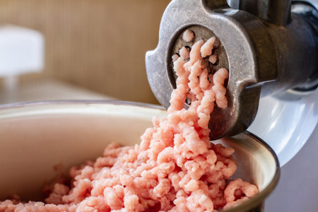 Minced meat coming out of a metal grinderの写真素材