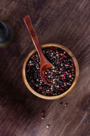 Mix of peppers with peas in a wooden cup with a spoon on a wooden background, top viewの写真素材