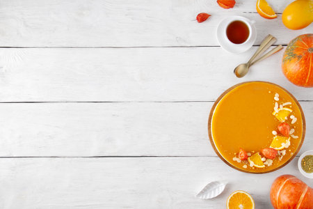 White wooden plank background with pumpkin, pumpkin pie, orange and tea, bright, top view.の写真素材