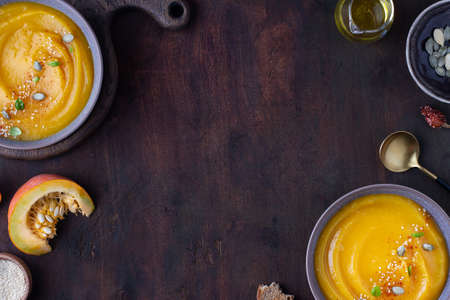 Wooden background, on it pumpkin soup in plates, top view, copy spaceの写真素材