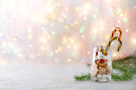 Christmas background with sweets, gingerbread, marshmallows and caramel sticks in a glass and bokeh, copy spaceの写真素材