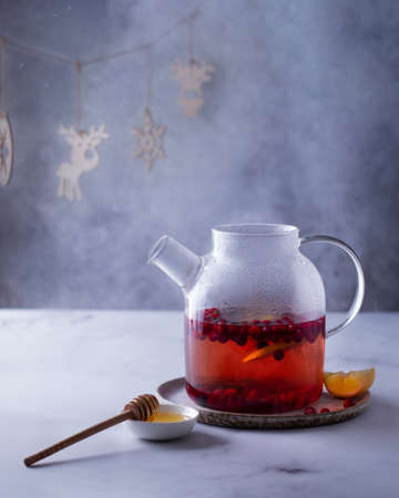 Fruit tea in a glass teapot on a table in a cold room, christmas garlandの写真素材
