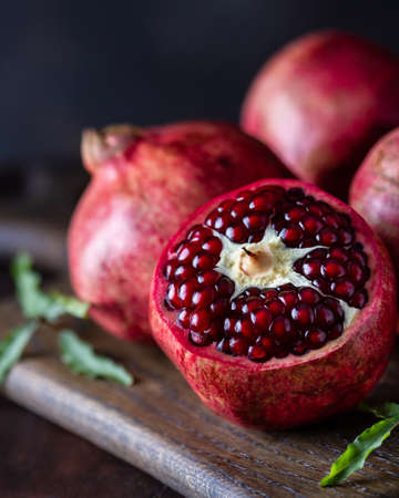 Ripe pomegranates on a wooden board, dark photo, close-upの写真素材