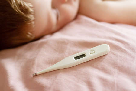 Thermometer with temperature near a sleeping sick child on a pillowの写真素材