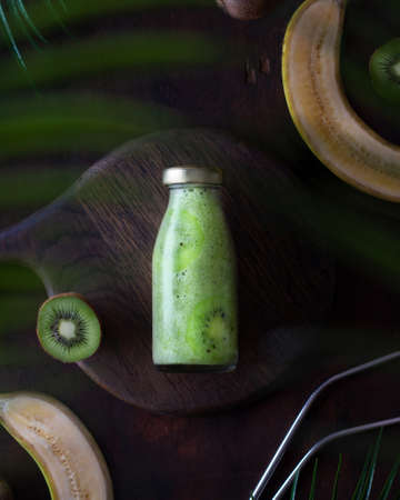 Green smoothie in a bottle lies on a wooden background, dark photoの写真素材
