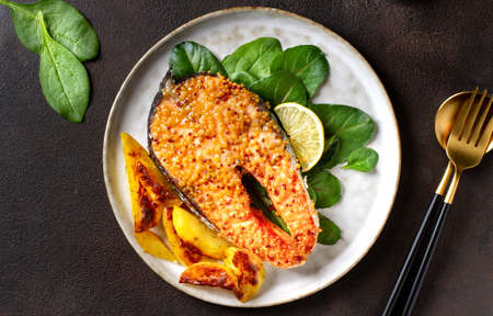 Salmon steak baked on a plate with potatoes and herbs