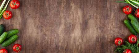 Wide wooden brown background with cucumbers and tomatoes, copy space