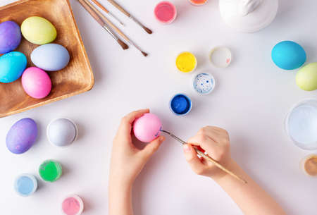 The child paints colorful eggs for Easter with a brush, top viewの写真素材