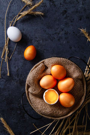 Chicken eggs in a basket with burlap on the floor with straw, in a broken yolk