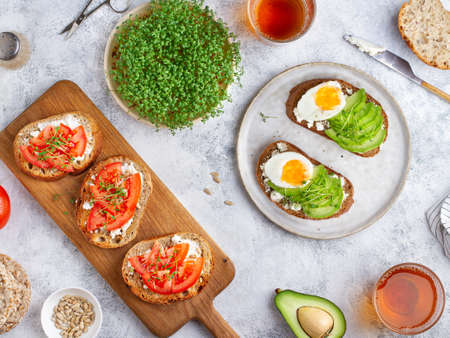 Healthy snacks: bruschetta with avocado, tomatoes and egg, microgreens, on the table, top viewの写真素材
