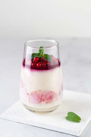 Dessert of cream and berries in a glass on a light background