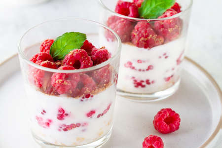 Yogurt with raspberries and mint in a glass, close-up