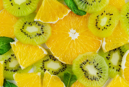 Texture from slices of tropical fruits oranges, kiwi and mint leaves, top viewの写真素材